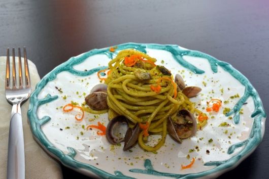 un plato de espaguetis con almejas y pesto en un restaurante
