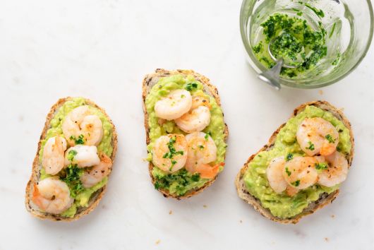 tres tostas con aguacate y gambas sobre una mesa