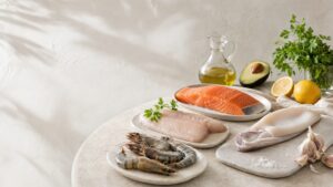 Lombo de salmão, filé de peixe branco, camarões e lula servidos crus à mesa com azeite, abacate, limão e salsa.